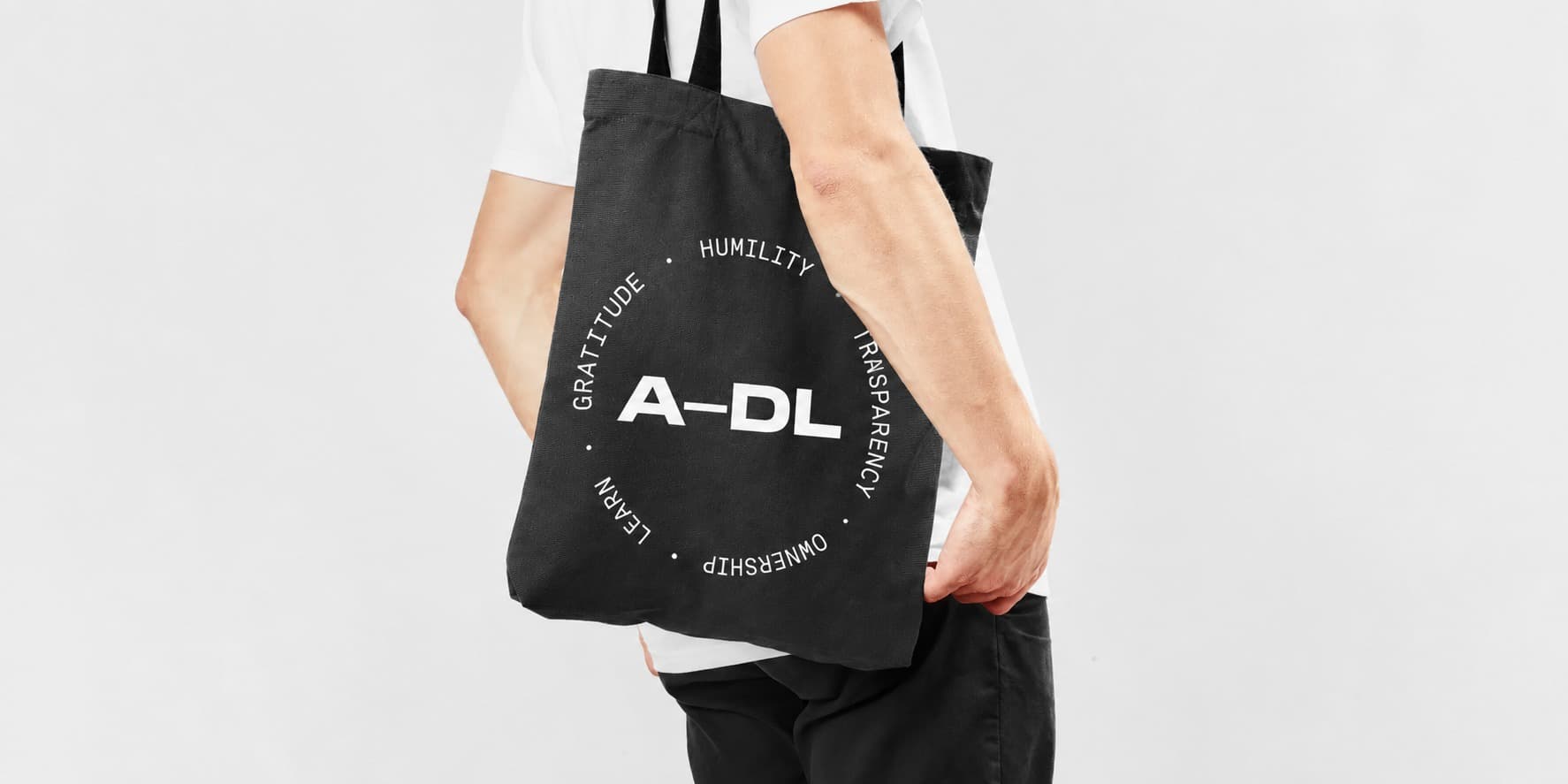 A−DL tote carrying the secondary mark · the daily artifact for the team